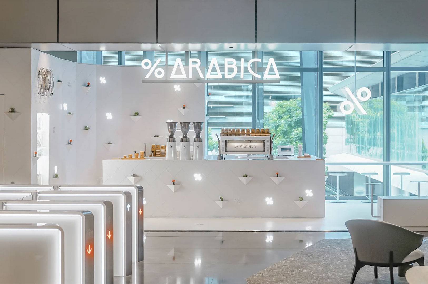 % ARABICA coffee shop interior featuring a white counter, minimalist design, and bright lighting near glass windows.