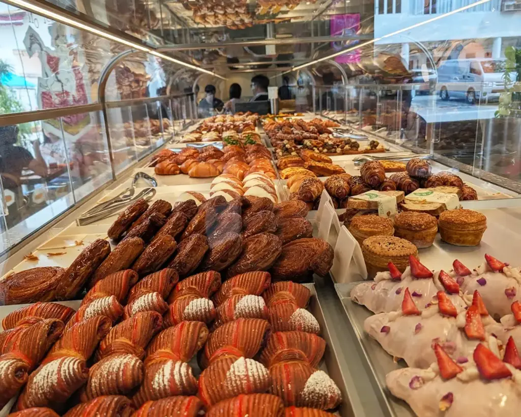 A bakery display filled with an array of pastries, including croissants, pastries topped with strawberries, and other baked treats. The setting is bright and inviting.