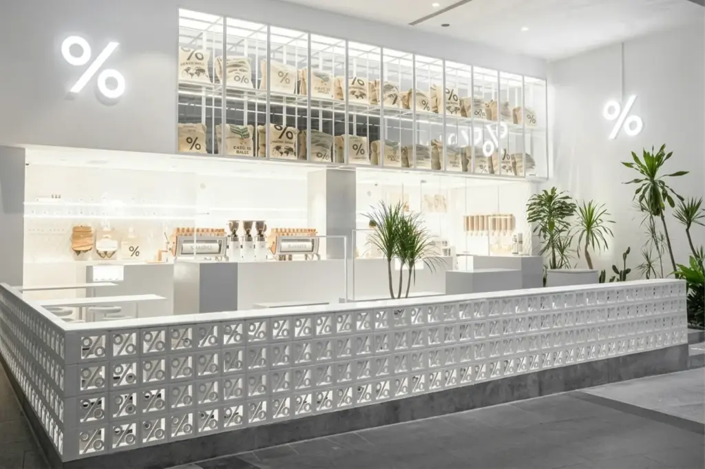 Spacious interior of a % ARABICA store featuring a high wall display of stacked coffee bean bags.