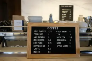 A coffee shop interior featuring a counter with a sign displaying the coffee menu.
