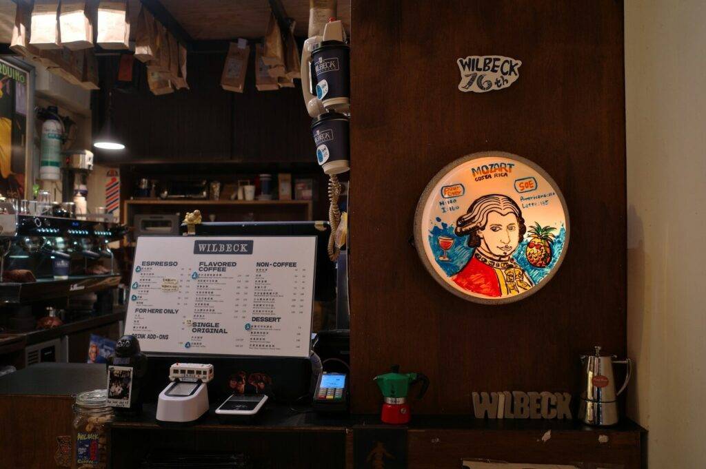 A coffee shop interior featuring a wall-mounted picture of a man and a visible coffee menu.