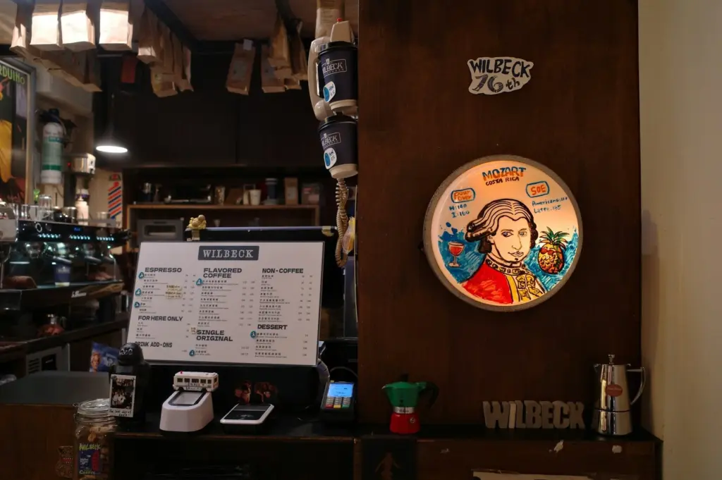 A coffee shop interior featuring a wall-mounted picture of a man and a visible coffee menu.