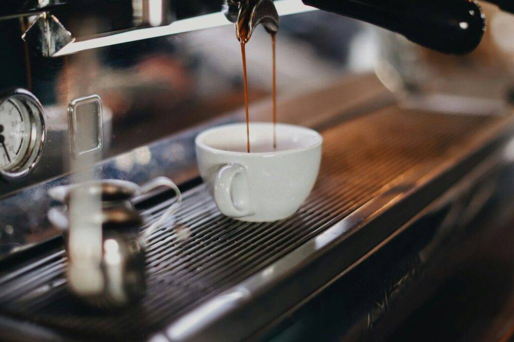 A coffee cup is being poured into an espresso machine, ready to brew a fresh shot of espresso.