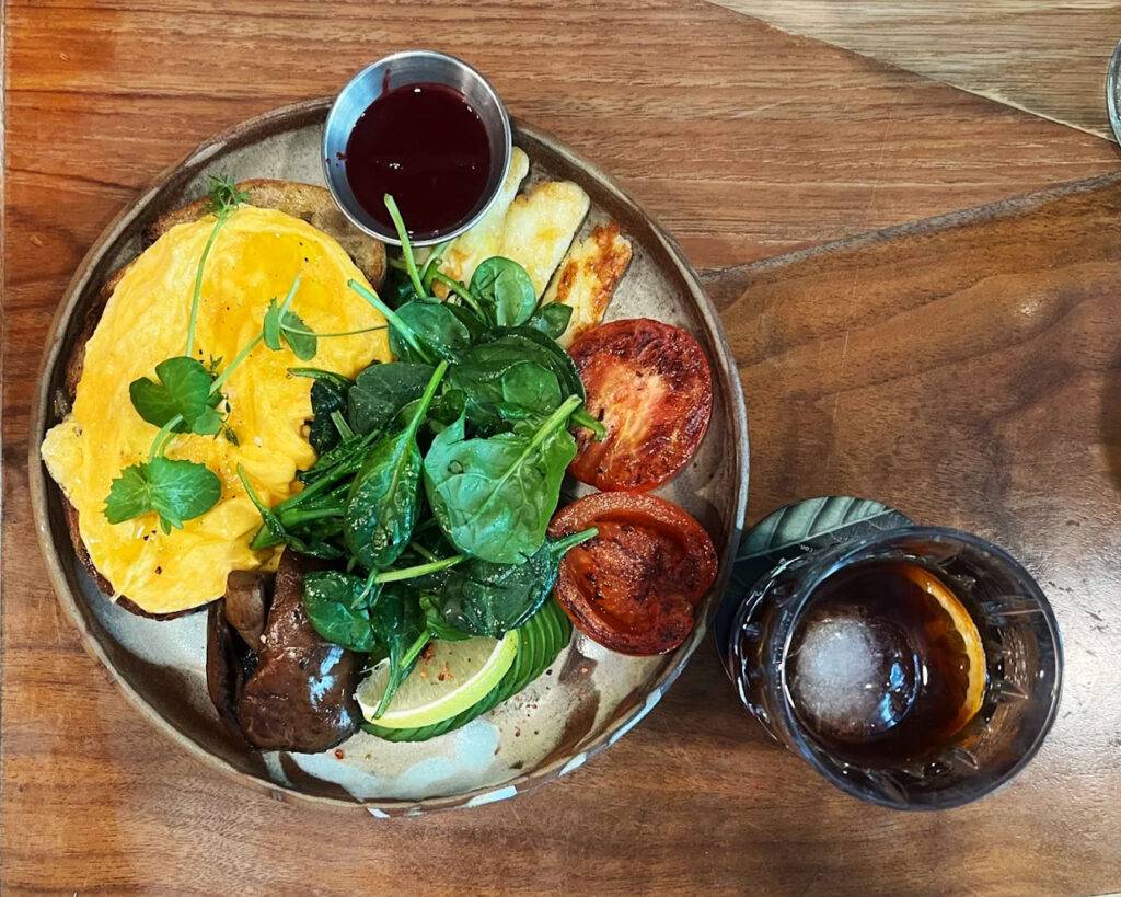 A traditional English-style breakfast with sausages, eggs, grilled tomatoes, and toast, served neatly on a white plate for a timeless look.
