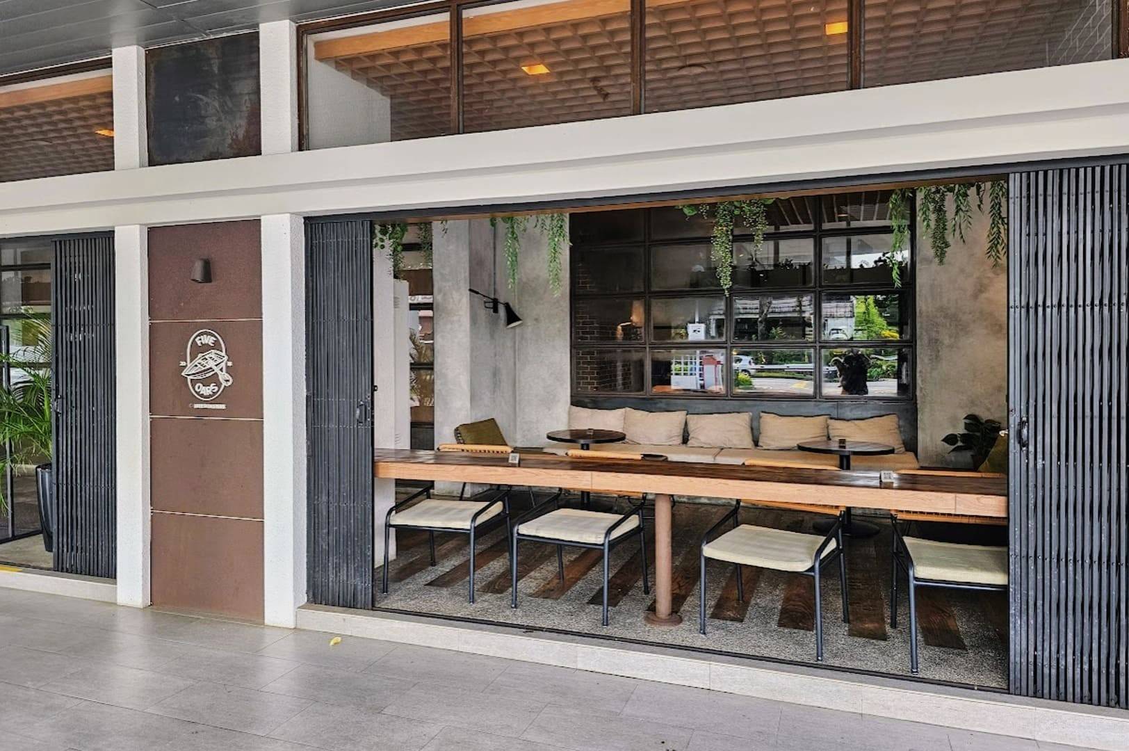 Five Oars Coffee Roasters, showcasing a large glass entrance and rustic wooden tables for dining.