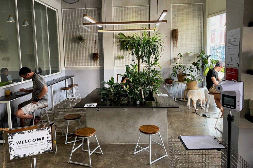A welcoming restaurant scene at Five Oars Coffee Roasters featuring a table, chairs, a dog, and a "Welcome" sign.