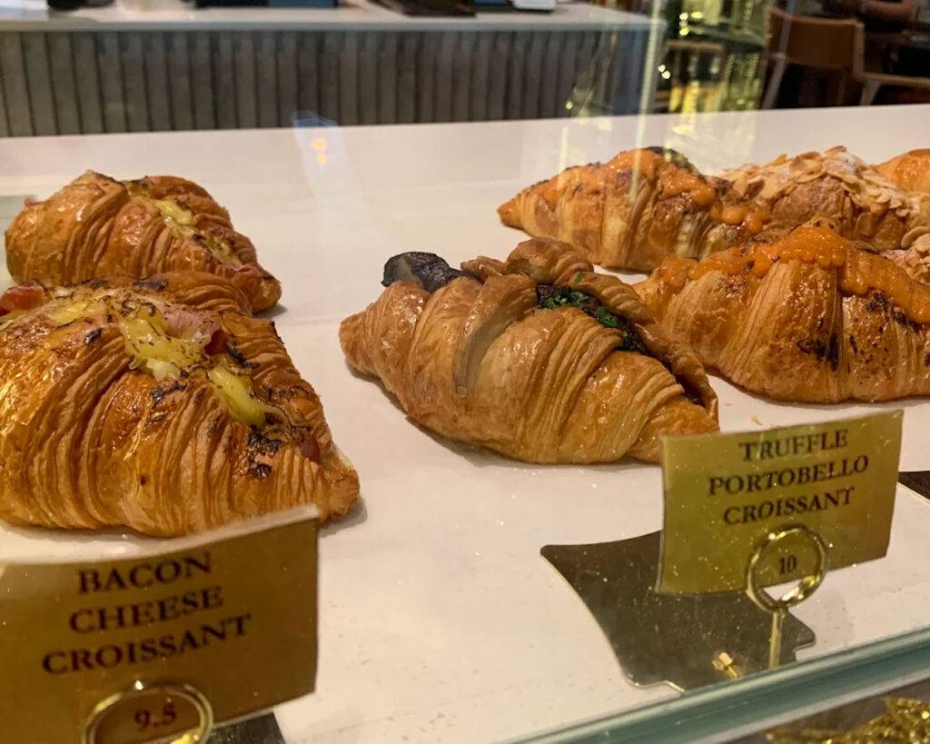 A flaky, golden croissant infused with aromatic truffle, presented whole on a plate to highlight its crisp layers and buttery texture.