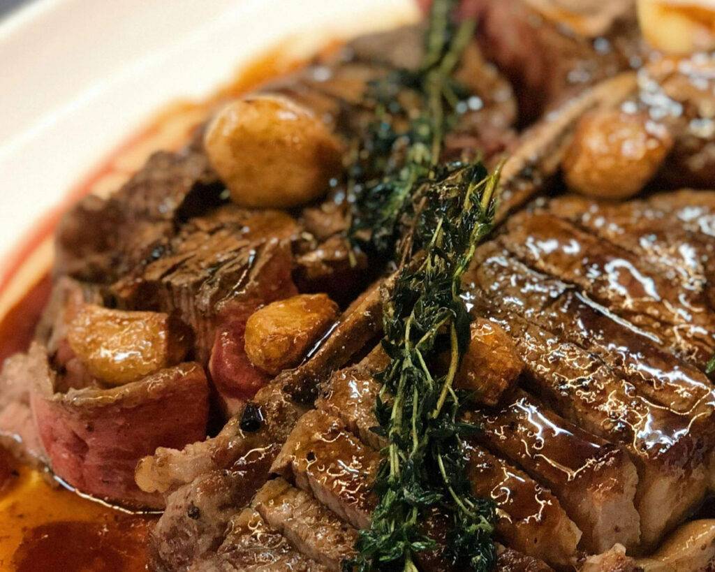 A tender, seared steak served with simple sides, highlighting the café’s focus on quality ingredients and clean, rustic presentation.