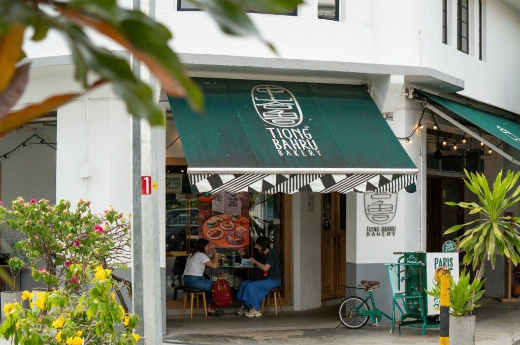 A cafe named Tiong Bahru Bakery with a green awning and a bicycle parked in front.
