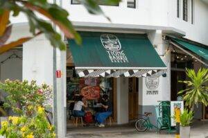 A cafe named Tiong Bahru Bakery with a green awning and a bicycle parked in front.