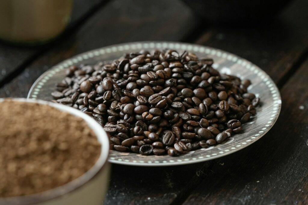 A plate featuring dark roasted coffee beans alongside freshly ground coffee powder.