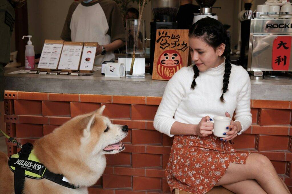 A woman relaxes in a chair next to a dog at a Puppy Cafe, enjoying the friendly atmosphere.