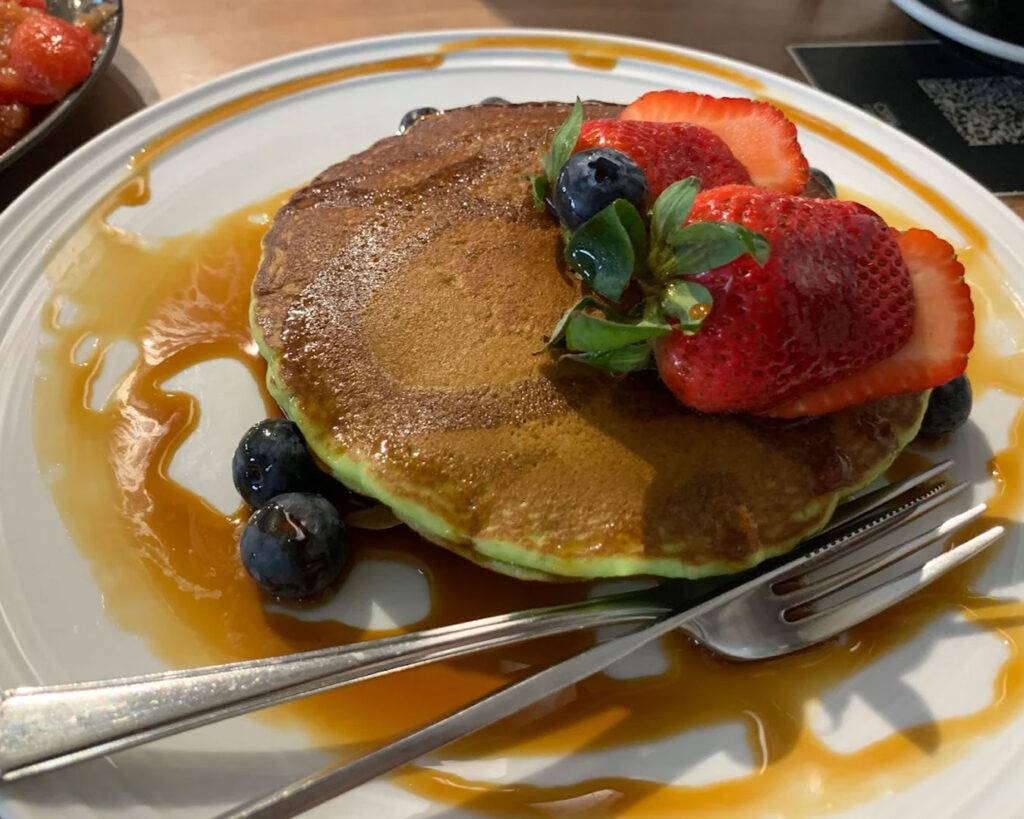 A fluffy pancake topped with fresh strawberries and golden honey, blending fruity brightness with natural sweetness on a classic breakfast favourite.