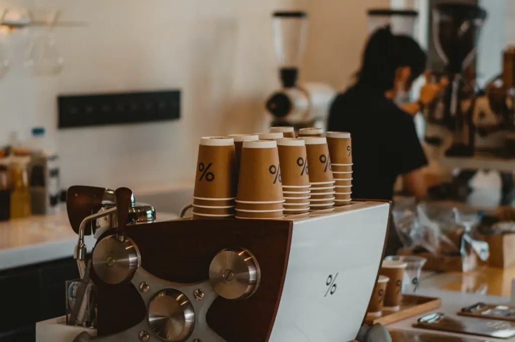 A coffee machine with stacked cups on top, set in a coffee shop in Singapore.