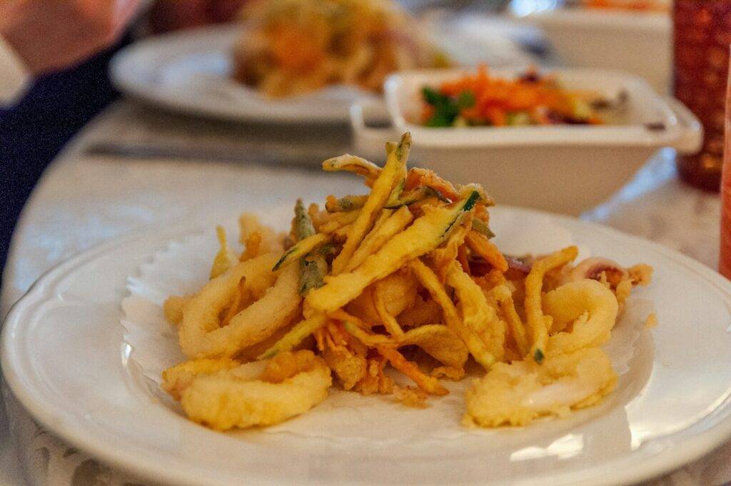 A vibrant Singapore brunch featuring a plate of fried squid accompanied by assorted vegetables.