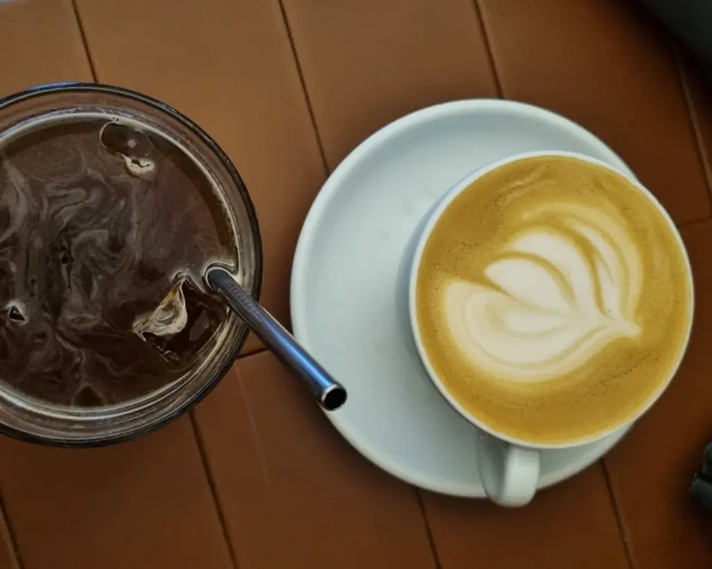 A stylish pairing of hot latte art and chilled coffee ice, presenting two contrasting textures and temperatures in one elegant café scene.