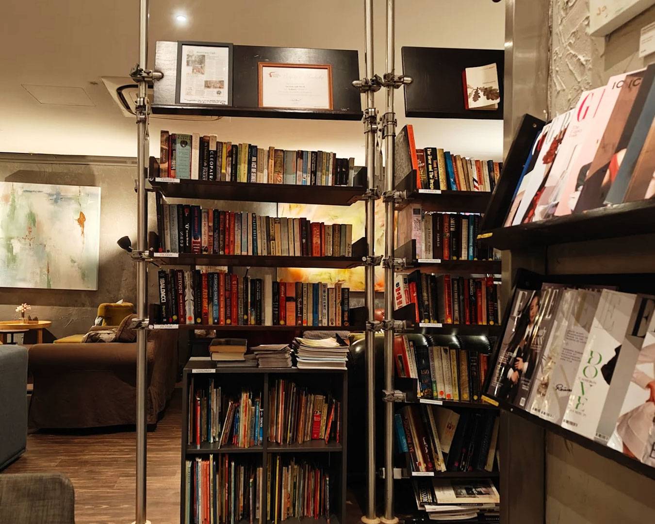 Wooden bookshelves lined with neatly arranged books, creating a warm and literary atmosphere inside The Book Cafe Singapore, inviting guests to browse while enjoying coffee and meals.