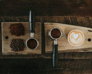 A neatly styled arrangement of roasted coffee beans surrounding a warm cup of freshly brewed coffee, highlighting the rich texture and deep brown tones of the beans.