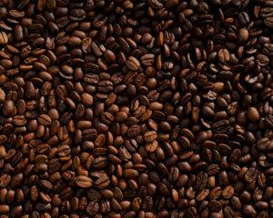 Close-up of fresh, dark roasted coffee beans, showing their rich texture and glossy surface, ready to be ground for brewing.