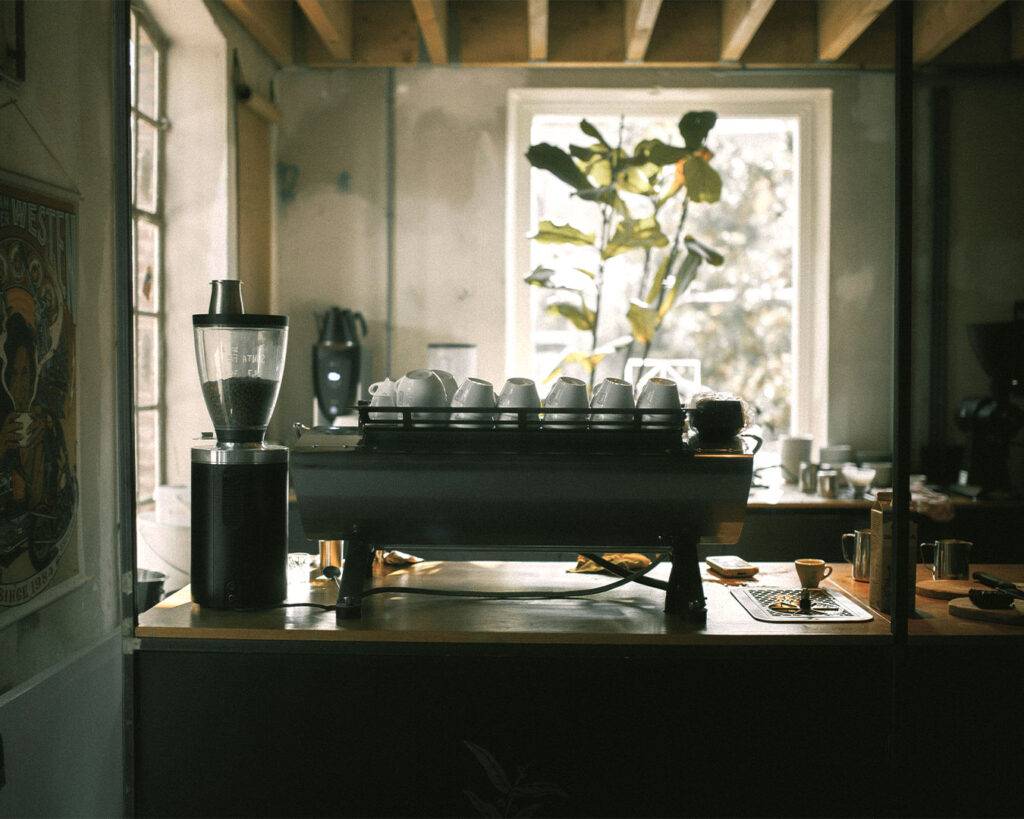 A cosy café interior with tables, chairs, and soft ambient lighting, creating a relaxed atmosphere where customers can enjoy coffee and conversation.