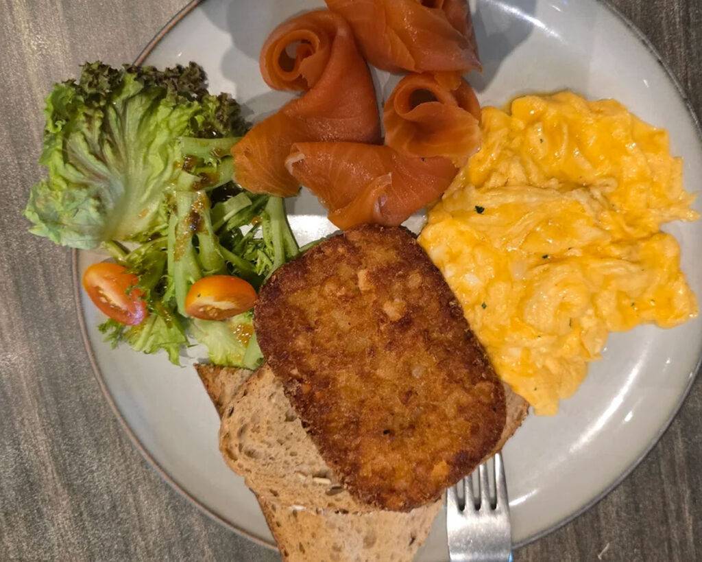 A fresh chicken Caesar salad served on a white plate, topped with grilled chicken, crisp romaine lettuce, crunchy croutons, and creamy dressing, presented in a bright and appetising style.