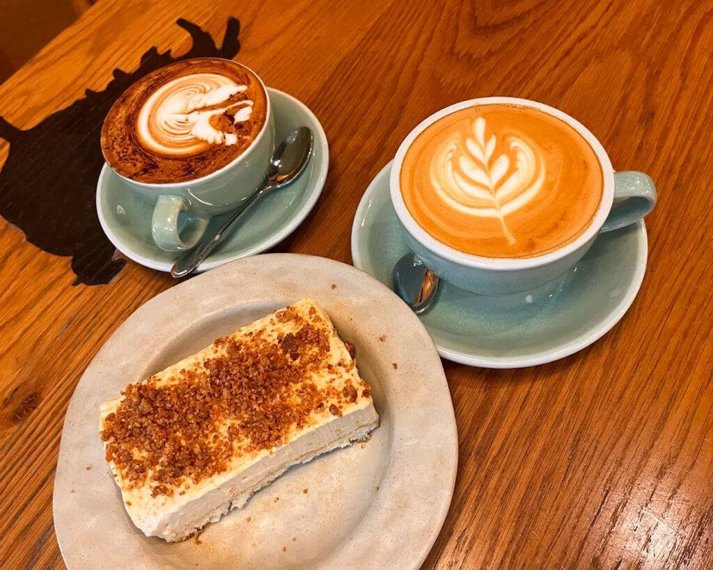 A cup of freshly brewed coffee from Common Man Coffee Roasters placed on a café table, styled as part of a simple breakfast setting.