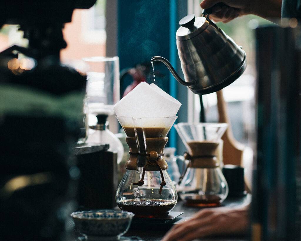 A display of different coffee brewing tools, including a pour-over dripper, French press, and kettle, arranged neatly to show various ways of making coffee.