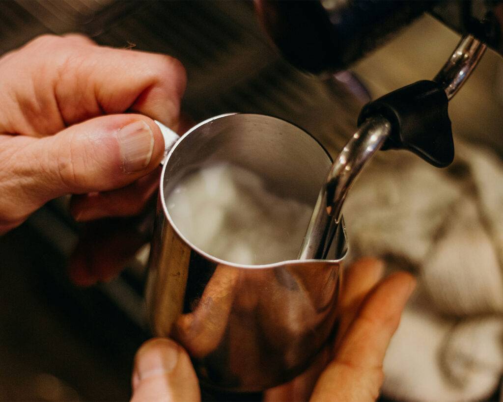 Barista steaming milk with a frothing wand, creating a creamy, velvety texture ready for a latte or cappuccino.