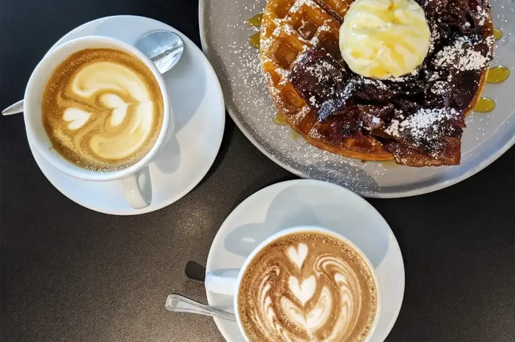 Two cups of coffee served alongside a waffle topped with a scoop of ice cream, blending warm and cold elements for a delightful dessert-style treat at Columbus Coffee Co.