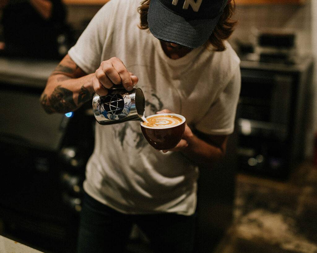 A skilled barista crafting intricate latte art with steady hands, showing expertise and attention to detail.