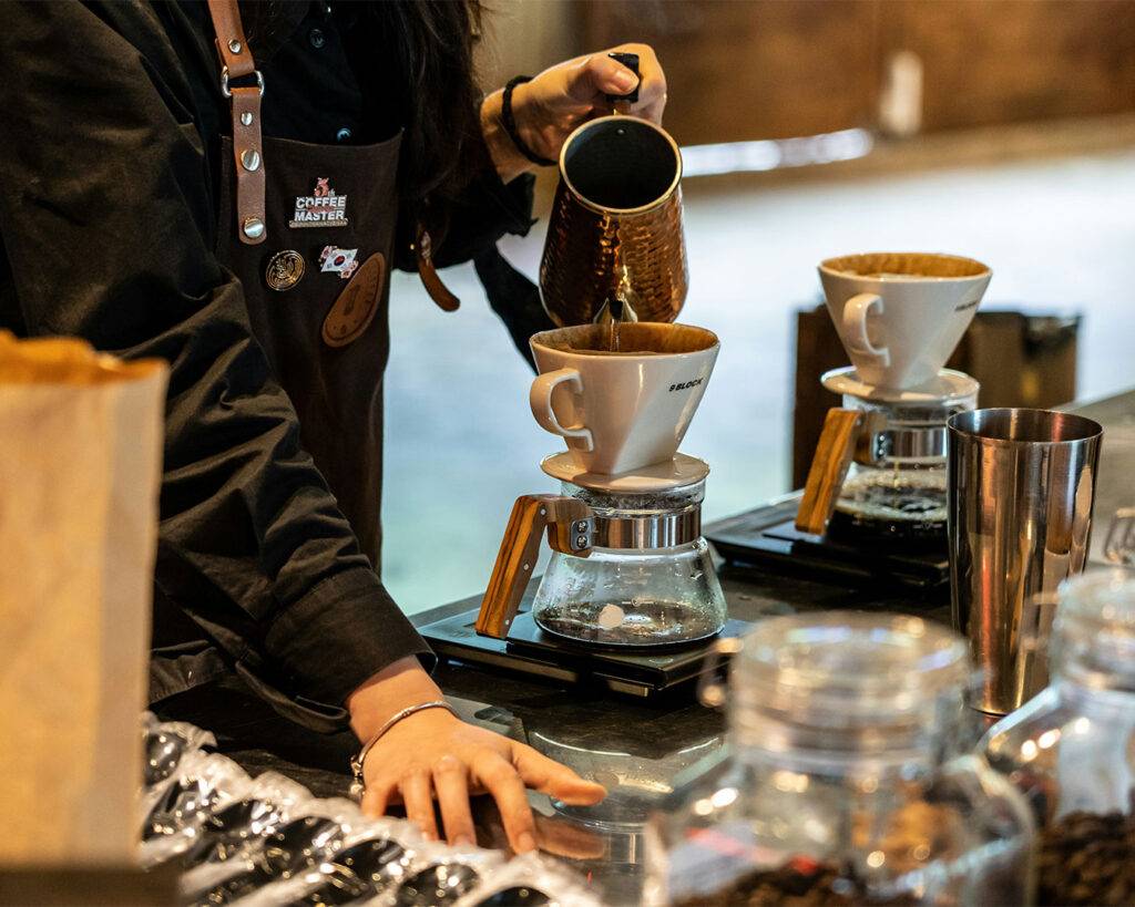 Barista carefully pouring hot water over coffee grounds, demonstrating precision and focus in the brewing process.