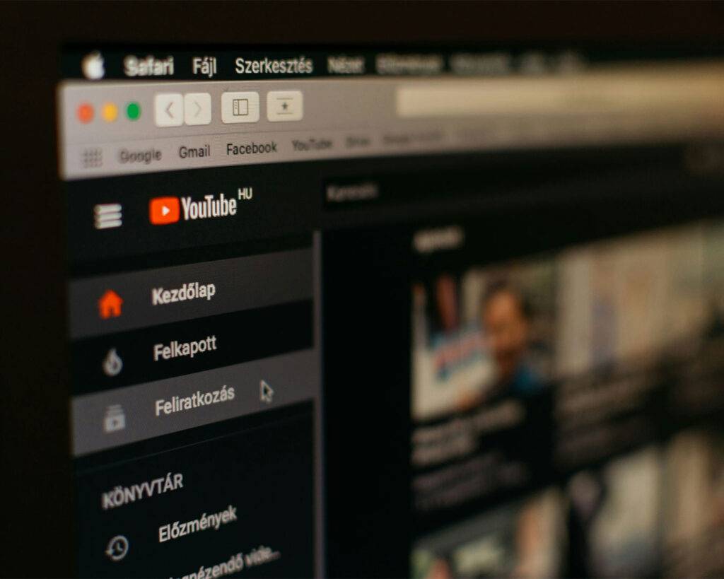 An open laptop displaying the YouTube homepage on its screen, placed on a desk and suggesting video browsing or content creation.