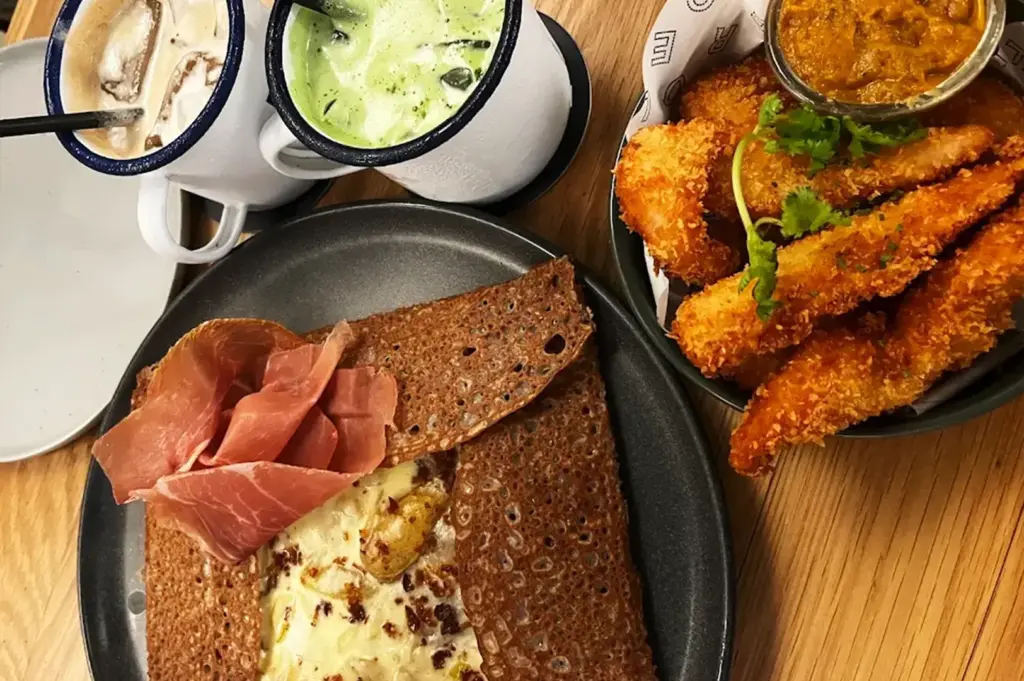 A classic buckwheat galette served with mushrooms and premium ham, accompanied by fried fish fingers for a refined and balanced dish at French Fold.