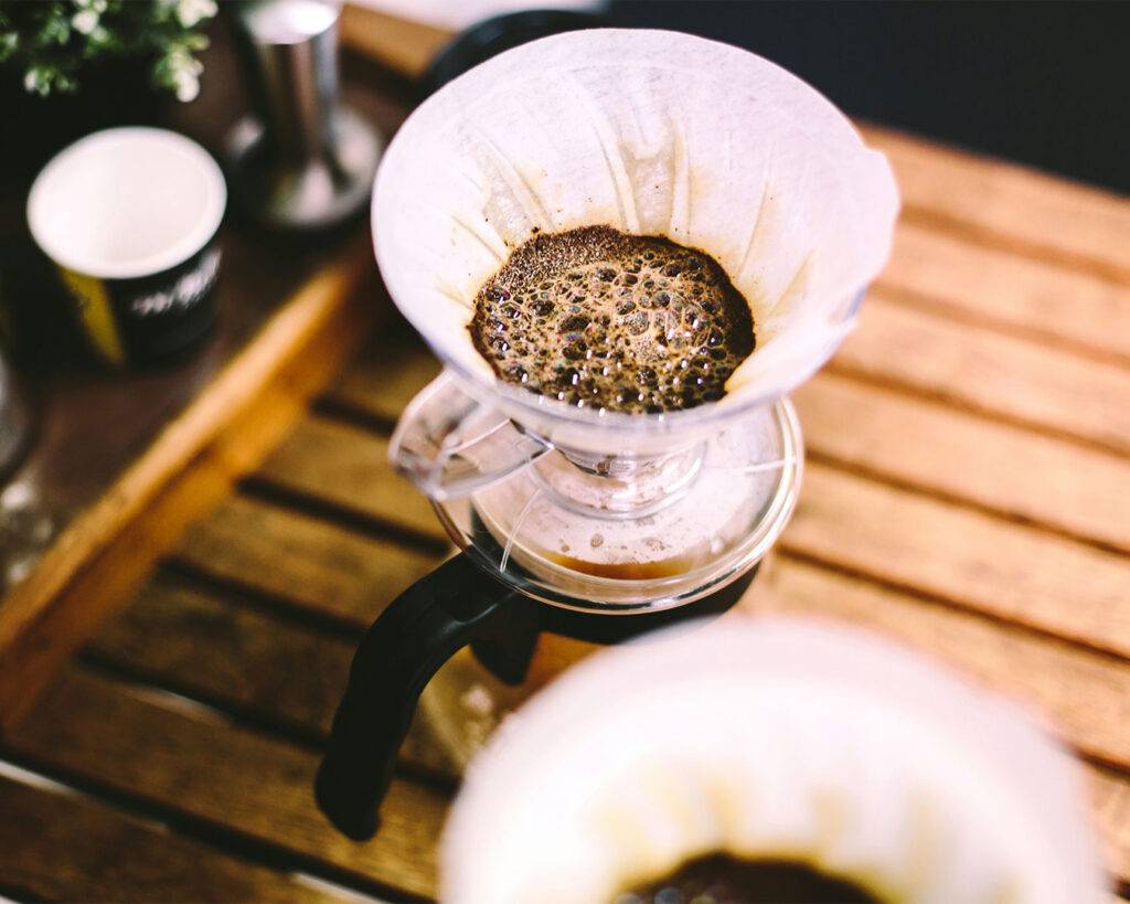 Freshly brewed coffee dripping through a filter into a glass container, showing the slow and smooth extraction process.