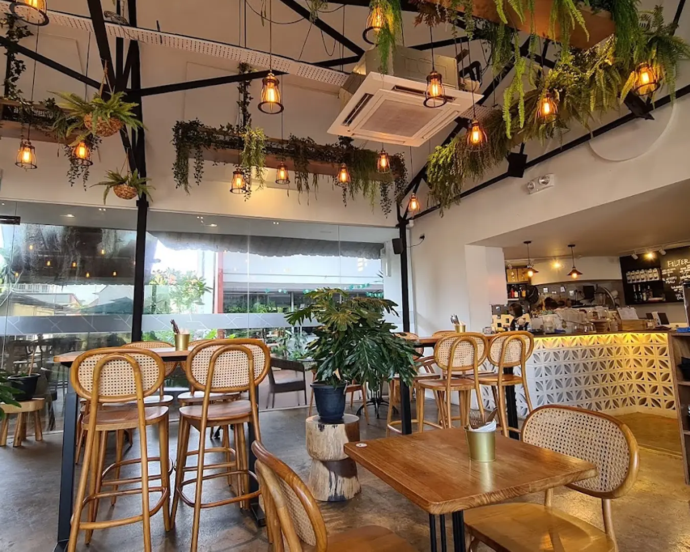 A cosy garden café interior filled with natural light, featuring wooden furniture, lush greenery, and soft earthy tones that create a calm, relaxing atmosphere—perfect for a quiet coffee break or casual