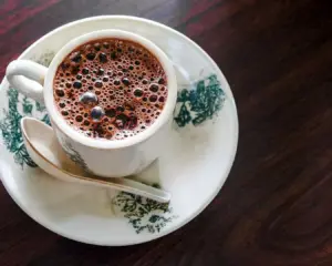 A freshly brewed cup of coffee placed on a wooden table, in a calm café setting