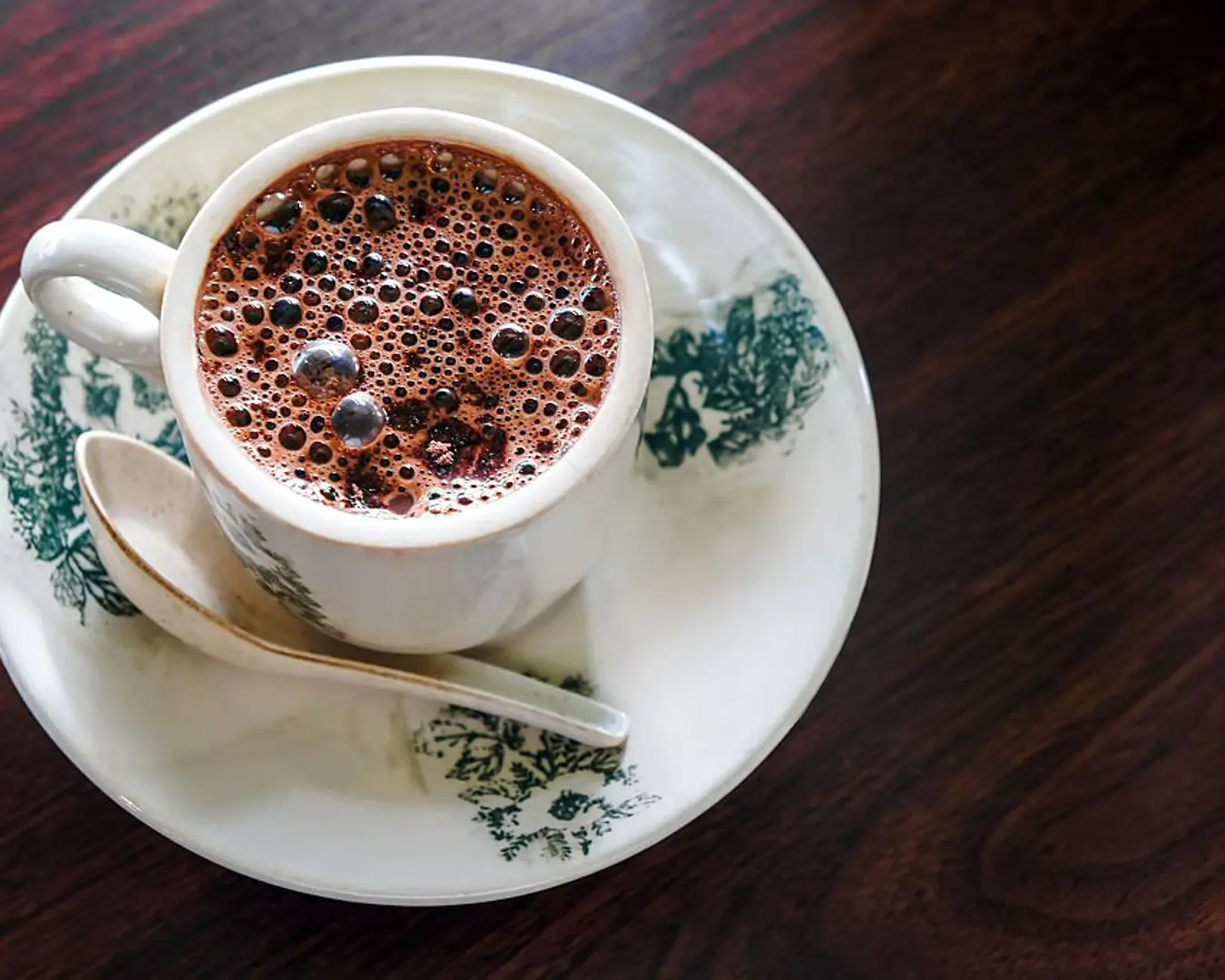 A freshly brewed cup of coffee placed on a wooden table, in a calm café setting