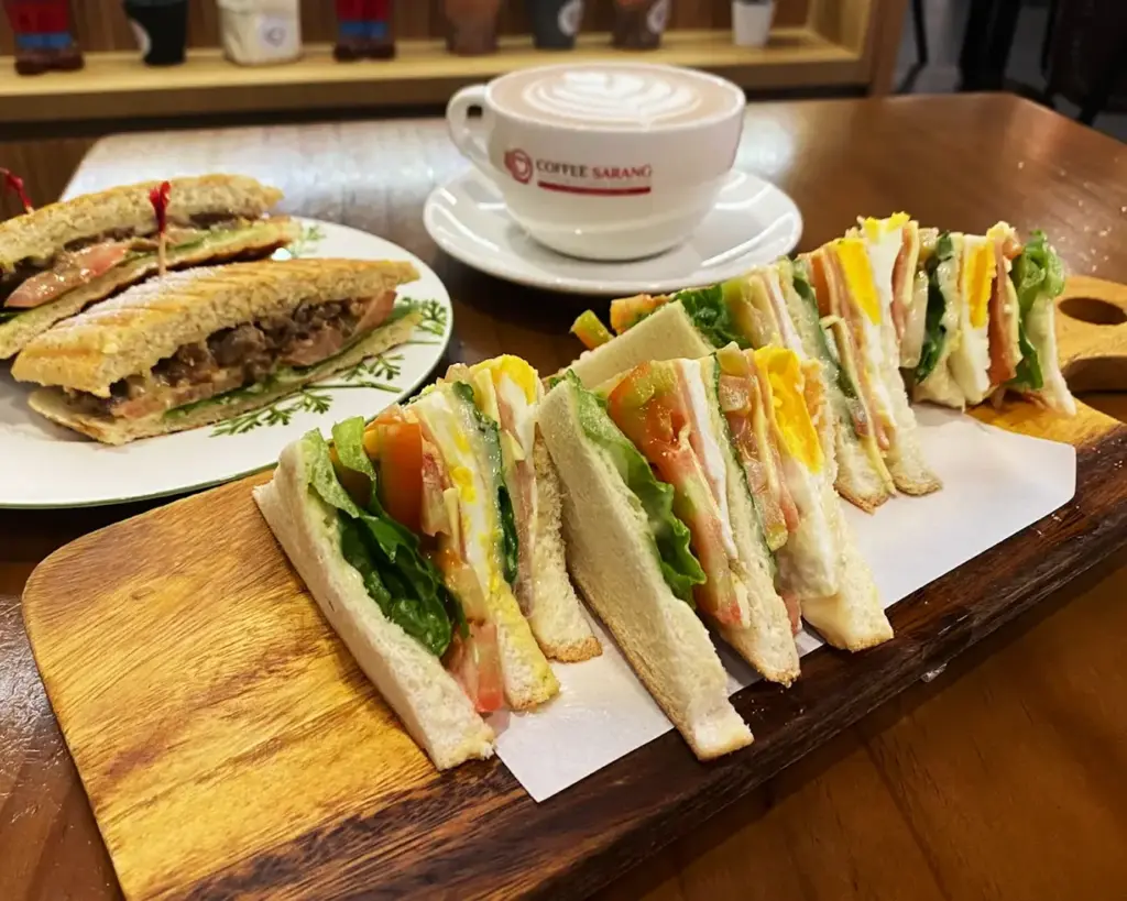 A freshly prepared sandwich served alongside a cup of hot coffee, neatly arranged on a table, highlighting a simple yet comforting café meal perfect for a casual break.
