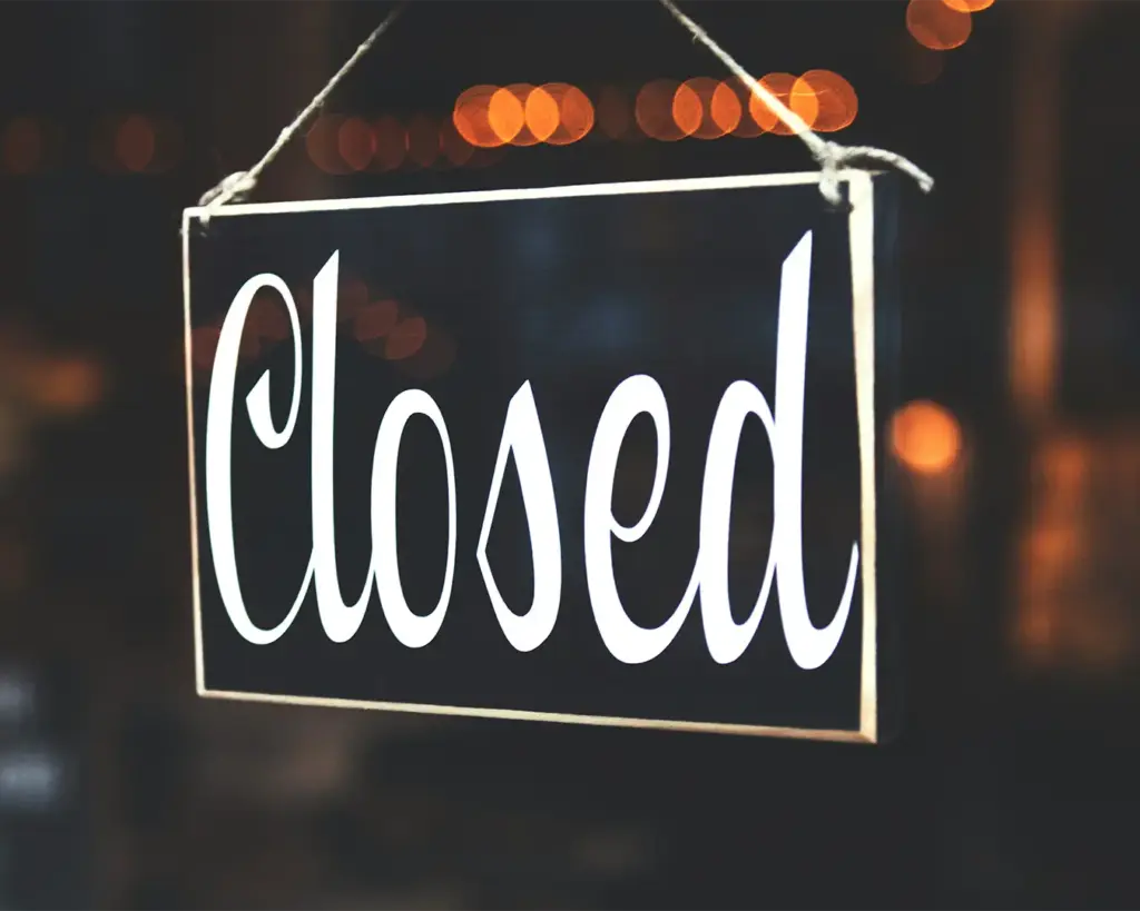 A “Closed” sign hanging on a glass door, indicating the café or shop is not currently open to customers, typically placed at the entrance to inform visitors of operating hours.