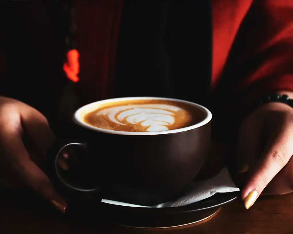 A hand gently holding a warm cup of coffee, suggesting a quiet moment of relaxation and enjoyment.