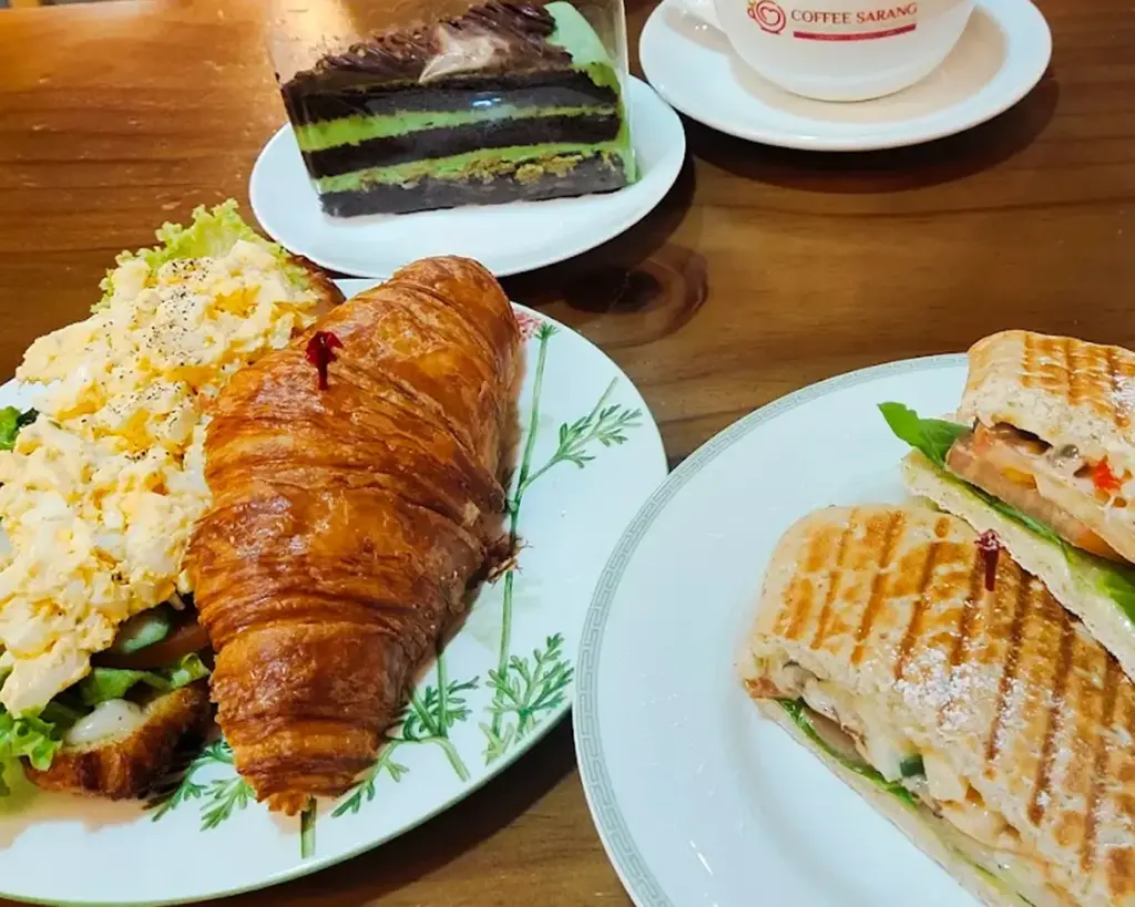 A golden, freshly baked croissant with flaky layers, filled with eggs, showcasing the café’s warm and satisfying breakfast-style pastry.