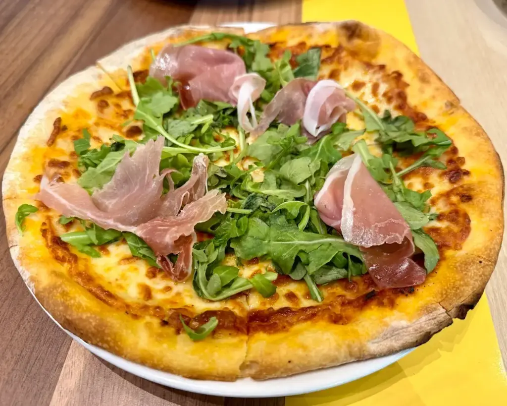 A freshly baked pizza topped with colourful vegetables and slices of meat, melted cheese covering the crust, presenting a hearty and flavourful dish.