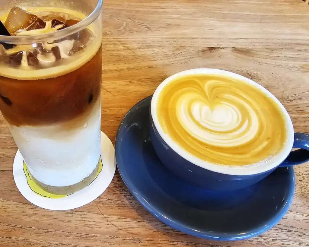 A warm cup of freshly brewed coffee paired with a chilled glass of iced coffee, showcasing two ways to enjoy a caffeine fix—one comforting and aromatic, the other refreshing and smooth.