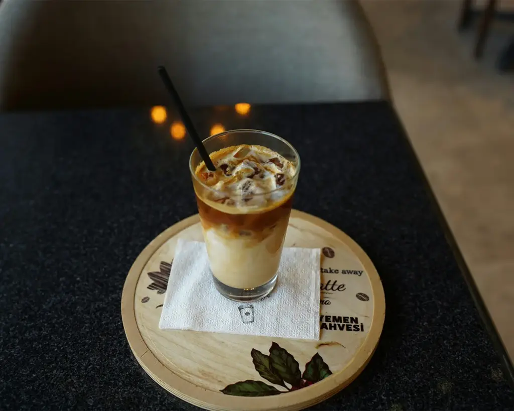 A clear glass filled with a creamy coffee latte, showing distinct layers of espresso and steamed milk for a smooth and comforting drink.