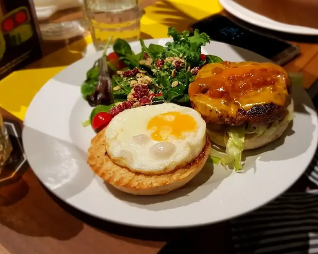A plated dish featuring toasted bread topped with a cooked egg, served alongside a fresh salad with leafy greens, creating a balanced brunch-style meal.