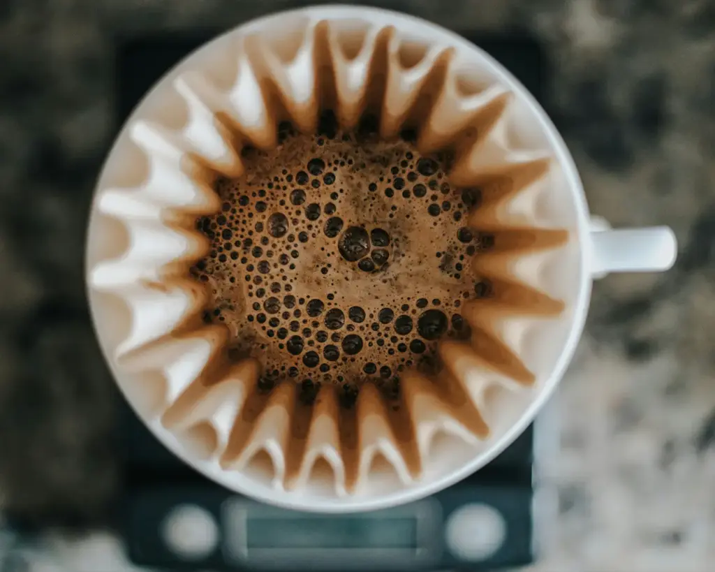 Fresh filter coffee being brewed through a paper filter into a glass carafe, illustrating the slow brewing process that enhances flavour and aroma.