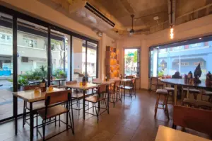 Interior view of Common Man Coffee Roasters at Joo Chiat Road featuring wooden furniture, floor-to-ceiling glass windows, and a bright, airy café atmosphere.
