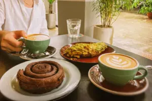 A remote worker enjoying a productive break with coffee and pastries at the outdoor seating of a café, highlighting the inviting atmosphere and peaceful place of Singapore's popular work-friendly café culture.