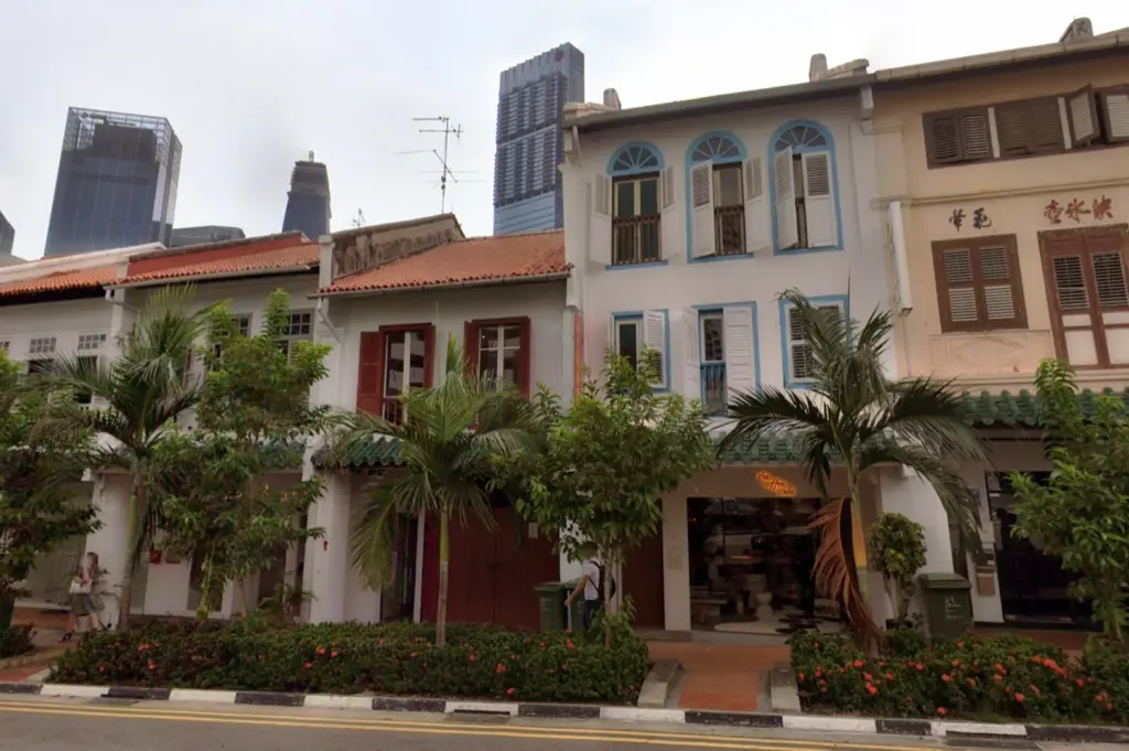 The exterior of The Coffee Code at Neil Road in Singapore, situated within a row of charming, traditional shophouses, contrasting with the surrounding modern city skyline.