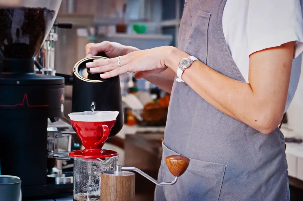 A barista using a gooseneck kettle for a manual pour-over coffee brewing technique, highlighting the commitment to the quality and passion, in artisanal coffee preparation and service in Singapore.